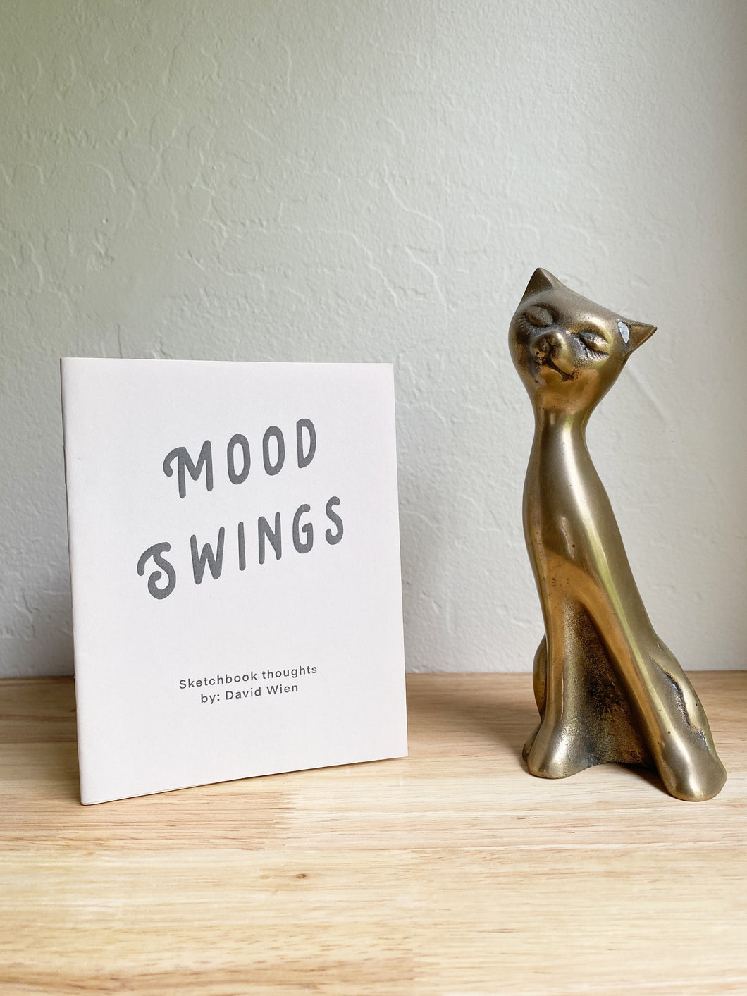 David Wien fine art print zine handmade recycled paper zine of folk art. Photo of a zine with a bronze cat. 